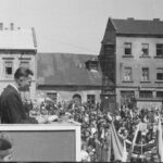 Czarnobiała fotografia przedstawia Rynek przełom lat 40./50. Wiec pierwszomajowy. W tle kamienica nr 2 (najniższa) własność rodziny Balisiów, przed którą w 1901 r. dokonano morderstwa małżeństwa Balisiów.